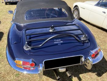 black jaguar e type xke convertible in a grassy field photographed from the rear with a revo-rack luggage rack fitted on a sunny day