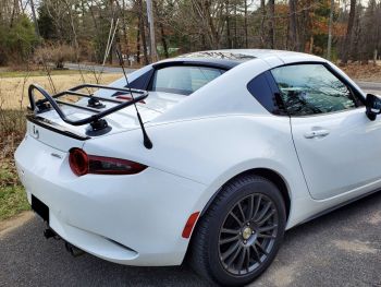 White Mazda Mx5 Miata RF with a luggage rack fitted on a driveway in the country photographed close at the rear